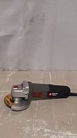 Side view of black and gray Porter Cable angle grinder with red accents and grinding disc attached