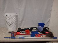 Full lot showing Bissell vacuum, brooms, various dusters, extension pole, laundry basket and blue pail.