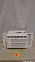 Front view of white Perfect Aire window air conditioner with control knobs and front vents visible.