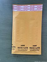 Single Eco-Lite 4x8 kraft bubble mailer showing front sealed flap with printed adhesive liner text, branding and dimensions.