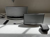 Overview of two dock units, one large silver and one small black, with remote and power adapter visible