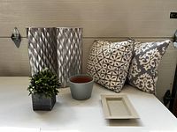 Wide photo showing all items in the lot: two tall silver-patterned vases, two grey patterned pillows, faux boxwood plant in square planter, grey ceramic planter, and rectangular dish.