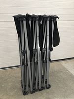 Folded black metal frame for rollaway bed with carry strap