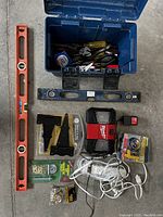 Top down photo showing open blue Mastercraft toolbox with tools inside (tape measure, screwdrivers, pliers), orange levels 36" and 24", Milwaukee radio, door lock kit, power bar and grommets.