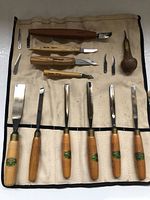 Full layout of all wood carving tools and carrying case on flat surface.