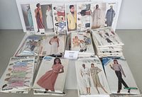 Multiple stacks of vintage women's sewing pattern envelopes from brands including Butterick, Burda, New Look, Simplicity, and Sears showing various garment styles.