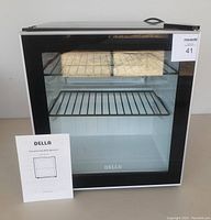 Front view of countertop refrigerator with glass door and instruction manual.