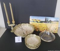 Photo shows large ceramic salad bowl and three matching small salad bowls with gold-tone petal design, plus glass wine decanter, onyx-look dual candle holder with two candles, and placemats with Tuscan landscape background.