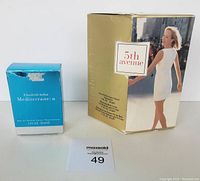 Photo showing both Elizabeth Arden fragrance boxes: 5th Avenue gift set in gold and white box with image of woman in white dress, and Mediterranean eau de parfum spray in blue box.