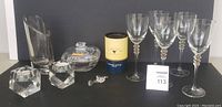 Photo showing all items in the lot displayed together including wine glasses, vase, covered dish, crystal rose in box, and candleholders