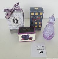 Photo showing all items in lot including boxed Violette Orange Blossom perfume, Guess Double Dare in box, LOLA solid perfume ring box, and purple glass Caithness perfume bottle.