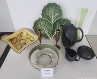 Wide shot showing all items in the lot including Wedgwood coffee set, brass candlesticks, Bordallo Pinheiro cabbage leaf dish, fruit bowl, square fruit dish, and tall green bud vase.