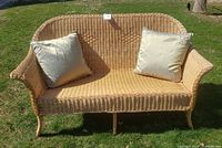 Front view of natural wicker loveseat with two green cushions
