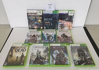 Overview photo of all ten Xbox 360 game cases displayed side by side, showing front covers with various game titles and artwork including Assassin's Creed series, Mass Effect, Skyrim, Bioshock, The Walking Dead and Dishonored.
