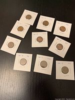 Ten Canadian pennies from 1970 to 1979, each in individual paper 2x2 holders with the year handwritten on them.