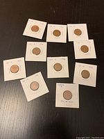 Photo showing 10 Canadian pennies from 1990 to 1999 individually mounted in coin holders, laid out on a dark surface.