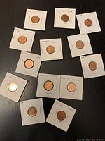 Photo of 13 Canadian pennies from years 2000 to 2012 individually mounted in white cardboard holders with labels showing year.