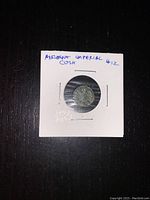 Front view of coin mounted in a white cardboard holder labeled 'Ancient Imperial Coin'