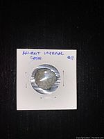 Front side of an ancient coin showing profile head, weathered surface, encapsulated in cardboard holder labeled 'Ancient Uniperal Coin #17'