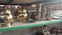 Wide view of the brass decor items on green shelf including pots, vases, candlesticks, and others.