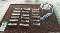 Overview of 12 cut glass chopstick rests, 6 non-matching rests, and vintage perfume bottle with pump and blue tassel.