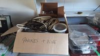 Photo showing a cardboard box labeled 'Phones + Wire' containing multiple coiled wires and cables in various colors.