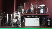 Vintage branded glassware on shelf including A&W mug, Samuel Adams glass, and others.