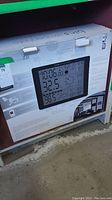 Front side of the box showing LCD display of the weather station indicating time, temperature, humidity, and wind data.