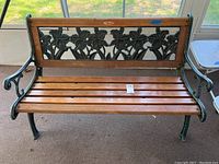 Front view of wood and metal bench highlighting the wooden slats and floral metal backrest design.