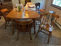 View of dining table with one side side chair and four arm chairs around it, with some household items on table