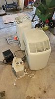 Photo showing the four items in the lot including the Frigidaire dehumidifier, humidifier, Patton and Duracraft heaters on a concrete floor
