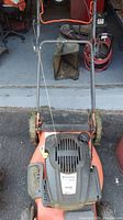 Top view of Husqvarna lawn mower showing handlebar, engine cover, wheels, and deck with visible dirt and signs of use.