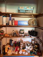 Shelved items including a food service film roll box, disposable masks box, tissue bag, coffee filters, pencils, batteries, small flashlights, and miscellaneous small items.
