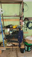 Overall view of shelf holding assorted power tools, ropes, and pump.