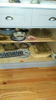 Wood cabinet shelf with assorted platters, bowls, decorative plates and placemats