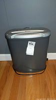 Front view of gray and silver Techko Identity Guard paper shredder on wooden floor with a label.