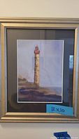 Close-up photo of a lighthouse-style framed painting, approximately 12x10 inches in a silver frame