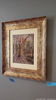 Side angle view of a framed nature scene artwork with textured antique carved gold frame, size 19x16 inches indicated.
