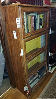 Front and side view showing the three glass-front compartments filled with books and magazines.