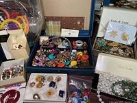 First photo shows a variety of colorful earrings, metallic rings, pins, and bracelets in different jewelry boxes and organizers.