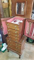 Open top section of the jewelry chest with mirror, pink felt lining and hanging necklaces
