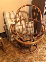 Front view of the rattan swivel chair showing the rounded back and striped cushions.
