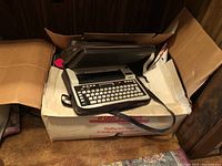 Brother EP20 word processor fully visible in black carrying case placed on two cardboard boxes.