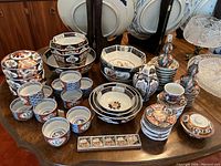 Wide overview of entire lot on table showing bowls, cups, plates, jars and vases
