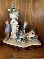 Front view showing four children seated and standing around a bench, puppies below, and a decorative urn and pedestal