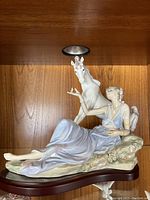 Full front view of the porcelain figurine on wooden base showing the reclining goddess and unicorn.