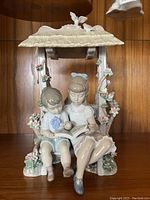 Front view of figurine showing children reading under arbor