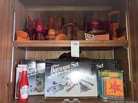 Bottom shelf showing two Shelton-Ware 6-piece barware set boxes and colorful napkin holder