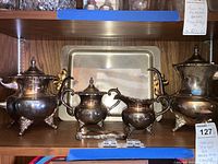 Full view of entire lot on wooden shelf showing four service pieces, tray and tongs