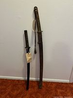Overall view of both swords side by side against wall and carpet